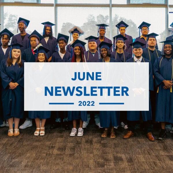 A group of graduates in navy blue caps and gowns stand together indoors. A large text overlay in the center reads June Newsletter 2022. Trees are visible through the windows behind them.