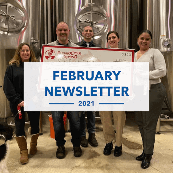 Five people stand smiling in front of metal brewing tanks, holding a large check. A blue banner across the image reads, FEBRUARY NEWSLETTER 2021.